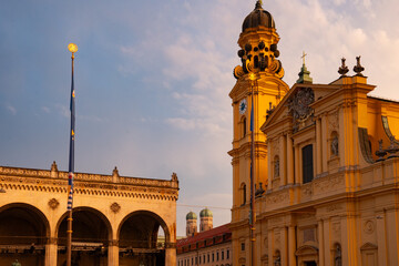 Fototapeta premium View from Odeonsplatz of the Feldherrnhalle and Theatinerkirche in the golden evening light. Munich, Bavaria, Germany. In the background the two towers of the Frauenkirche