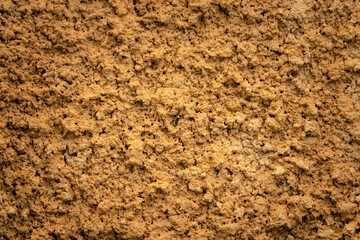 A close up of a brown surface with a lot of texture. The surface is rough and uneven, giving it a natural and earthy feel. The texture is so dense that it almost looks like a wall made of dirt or sand