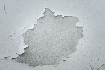 Fototapeta premium A white wall with a hole in it. The wall appears to be old and worn, with some paint peeling off