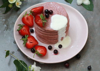 Delicious breakfast setting with a stack of homemade berry pancakes topped with fresh strawberries and cream. The vibrant colors and flowers create an appetizing and inviting summer morning scene