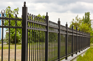Metal fence in the city park. Decorative black iron guardrail for protection, close up