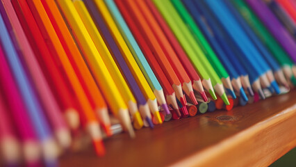 detailed close-up photograph of a colorful array of colored pencils neatly arranged on a wooden surface