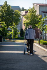 elder man walking outdoors with walker rollator