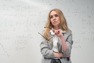 Fototapeta premium A Caucasian woman stands at a blackboard with written formulas.