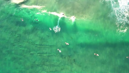 Top-down aerial view of surfers catching a wave on the Gold Coast