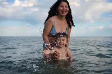 Summer holiday at sea, mother and child are happy swimming at su