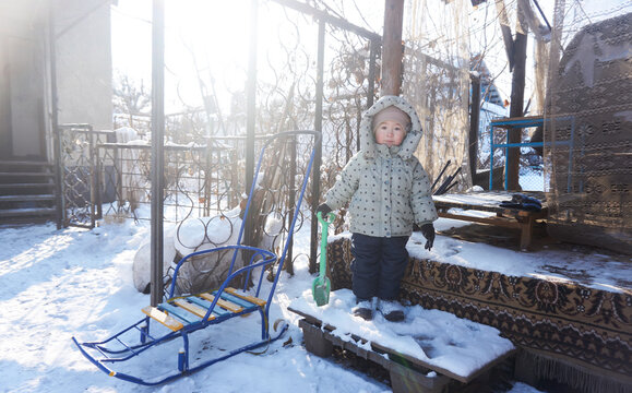 Сhild in winter plays with a shovel and snow