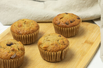 Four banana chocolate chip muffins on a cutting board