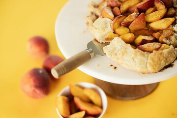 peach galette on a serving pedestal on a yellow background