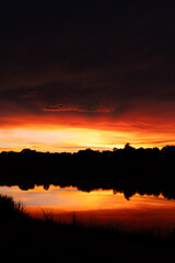 Dramatic sunset with vivid colors reflecting on a still lake