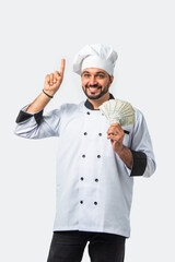 Smiling Asian Indian chef or professional cook with 500 rupee money fan, isolated white background