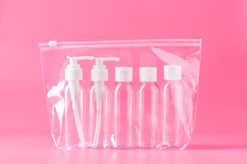 Five Clear Plastic Travel Bottles With White Pumps and Caps on Pink Background