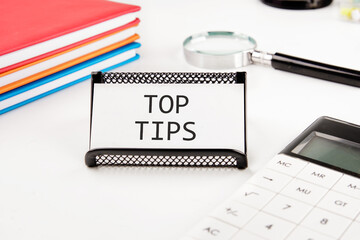 The phrase Top Tips on a business card in a stand on a white background