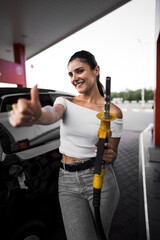 A woman fills a car with fuel at a gas station. Gas station service. Refueling concept. 