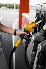 A woman fills a car with fuel at a gas station. Gas station service. Refueling concept. 