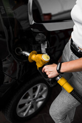 A woman fills a car with fuel at a gas station. Gas station service. Refueling concept. 