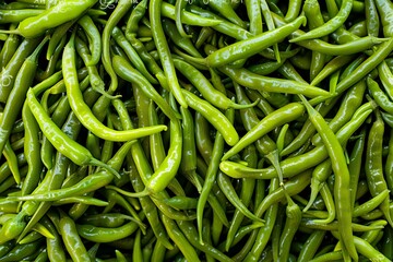 Top view of fresh green chili peppers for background, texture or pattern. Green chilli pile. Top down view of sweet legumes in a natural organic market. Sichuan cuisine with prime hot peppers in the s