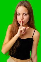 Naklejka premium Young Woman Making a Hush Gesture against green background