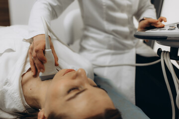 panoramic shot of doctor examining thyroid of female patient with ultrasound scan in clinic