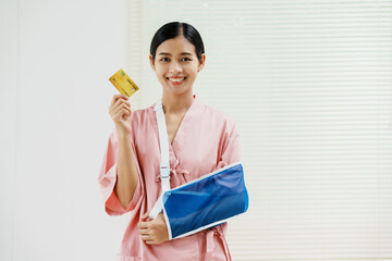 A young Asian female wearing a pink patient uniform stands isolated against a white wall...