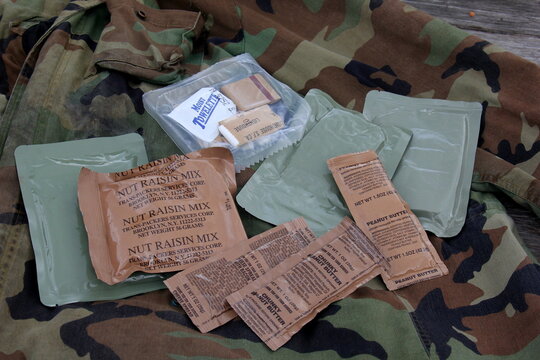 Riga, Latvia, - 23 June 2024 : Several Individual Food Rations for USA soldiers. Pack of Meal, Ready to Eat (MRE) food, USA army military food kit on the background of an army uniform