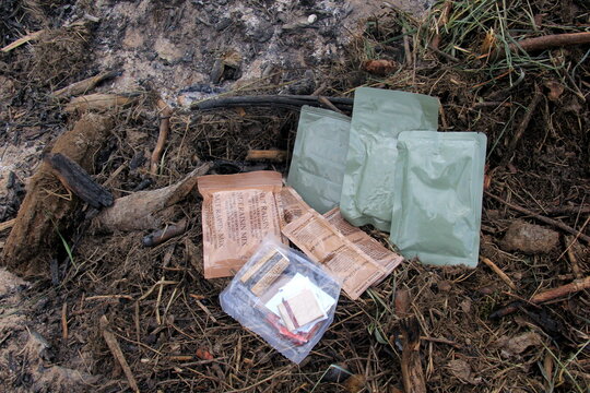 Riga, Latvia, - 23 June 2024 : Several Individual Food Rations for USA soldiers. Pack of Meal, Ready to Eat (MRE) food, USA army military food kit on the background of an old campfire