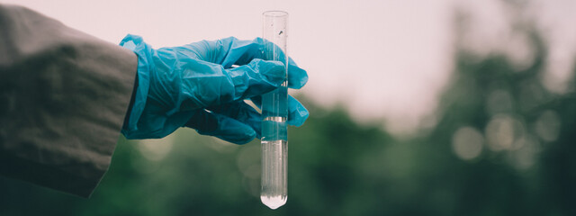 The outdoor researcher used a tube to collect water from nature, conducting scientific analysis to...