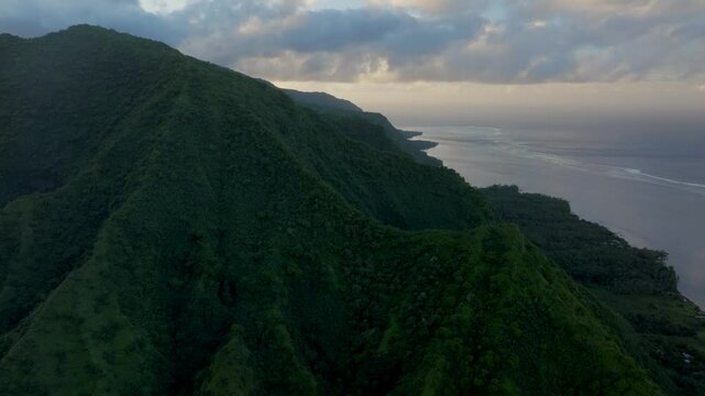 Teahupoo Tahiti across mountain peaks valley hills jungle coastline sunrise yellow clouds golden hour sunset aerial drone view French Polynesia WSL Surfing summer Olympic venue town village forward