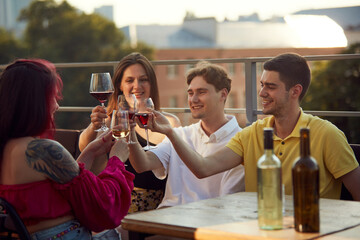 Vibrant moment of celebration as friends toast to their shared happiness under bright sun. Festive moment. Concept of party, Friday mood, celebration, summer holidays, relax.