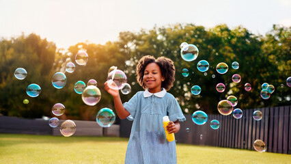 Fototapeta premium Portrait of Happy Child Playing with Soap Bubbles Outdoors