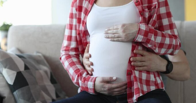 Man and woman are stroking belly in last month of pregnancy. Expecting child and family parental happiness concept