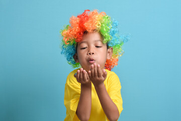 Cute little asian boy in clown wig isolated on blue background. copy space
