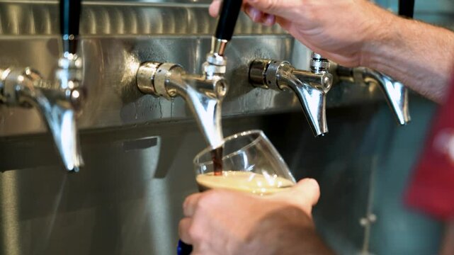 Man pouring a pint of dark stout beer from a tap at restaurant happy hour