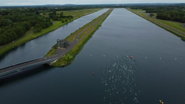 Drone shot of Triathlon at Dorney lake, triathletes swimming towards the transition area and cycling on the track