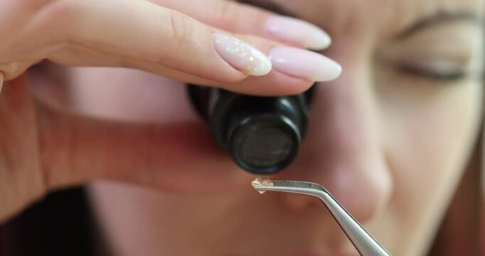 Female uses jeweler magnifier tool examining small diamond