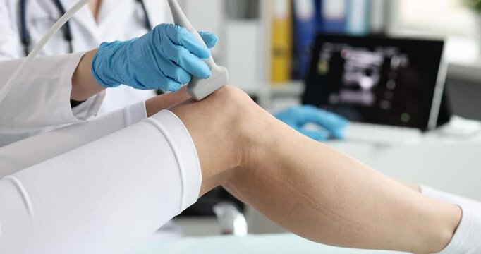 Doctor uses sonography to take sports x-ray of patient knee. Orthopedist during ultrasound diagnostics in medical office.