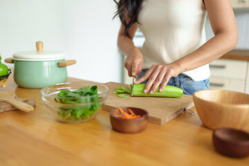 Diet to maintain figure. Fresh food is important for weight loss and perfect health. A woman is cutting vegetables to make a salad to eat at home in the kitchen. Concept of maintaining health at work