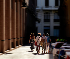 Women walking along a narrow, backlit street