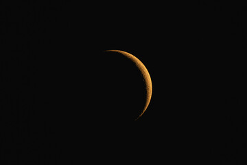 Blood moon crescent orange colored moon in high definition on dark space backround © Daan