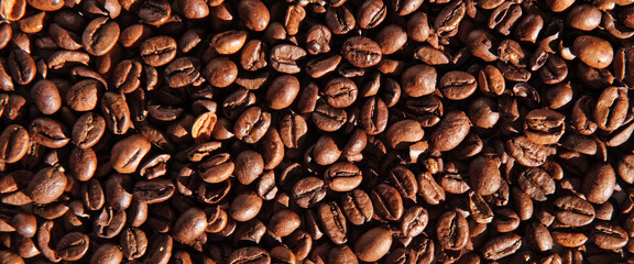 Coffee beans banner background. Texture of coffee beans close up. Dark brown roasted coffee is spinning. Abundance. Concept for coffee product advertising. Selective Focus. Border design, copy space