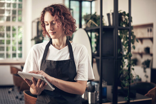 Beauty, salon and woman with tablet at work for job, planning and reading online booking info. Small business, person and stylist with tech in spa for client portfolio, research and hair care tips