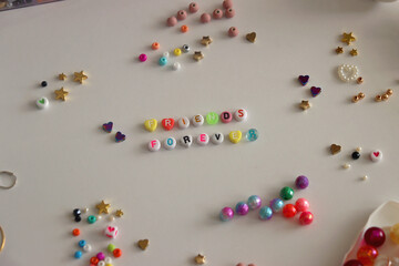 Friends forever written with colorful beads. Jewelry making supplies on the table. Making friendship bracelets concept. Selective focus.
