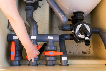 Unrecognizable woman adjusting valves on swimming pool filtration system