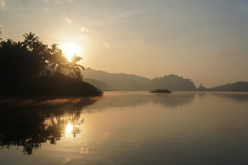 Obraz premium A beautiful morning view of sunrise over Sermo lake in Yogyakarta with a mountain in the background.