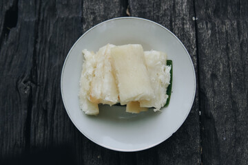 Boiled cassava or telo, Indonesian traditional snack, served on top of banana leaf and white plate.