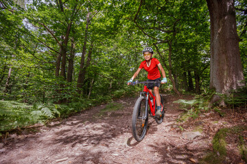 Naklejka premium Happy cyclist exploring the mountain forest on professional bike