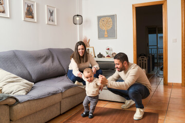 A family of three, a man, a woman and a baby, are playing in a living room
