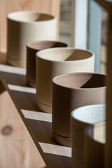 Ceramic pots displayed on a wooden shelter in a shop. Minimalist style.