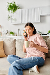 A mature woman in cozy homewear chats on a cell phone while relaxing on a couch.