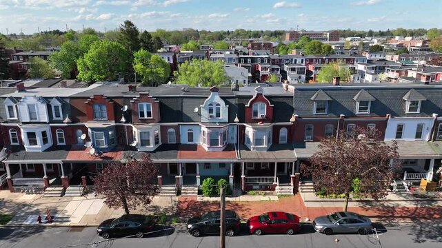 Historic row houses with distinct architectural details, tree-lined streets, and parked cars. Aerial truck shot in American city during spring.